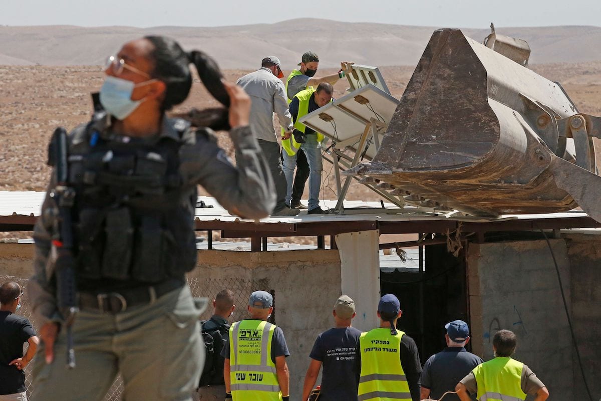 Men remove solar panels before Israeli authorities demolish the house and shack of a Palestinian family in the southern West Bank village of Khirbet Jinba on September 2, 2020, [HAZEM BADER/AFP via Getty Images]