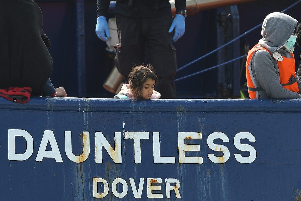 A girl stands onboard the DHB Dauntless tug boat as a group of migrants are brought to shore by the UK Border Force after illegally crossing the English Channel from France on a dinghy on 11 September 2020, in the marina at Dover, on the south coast of England. [BEN STANSALL/AFP via Getty Images]