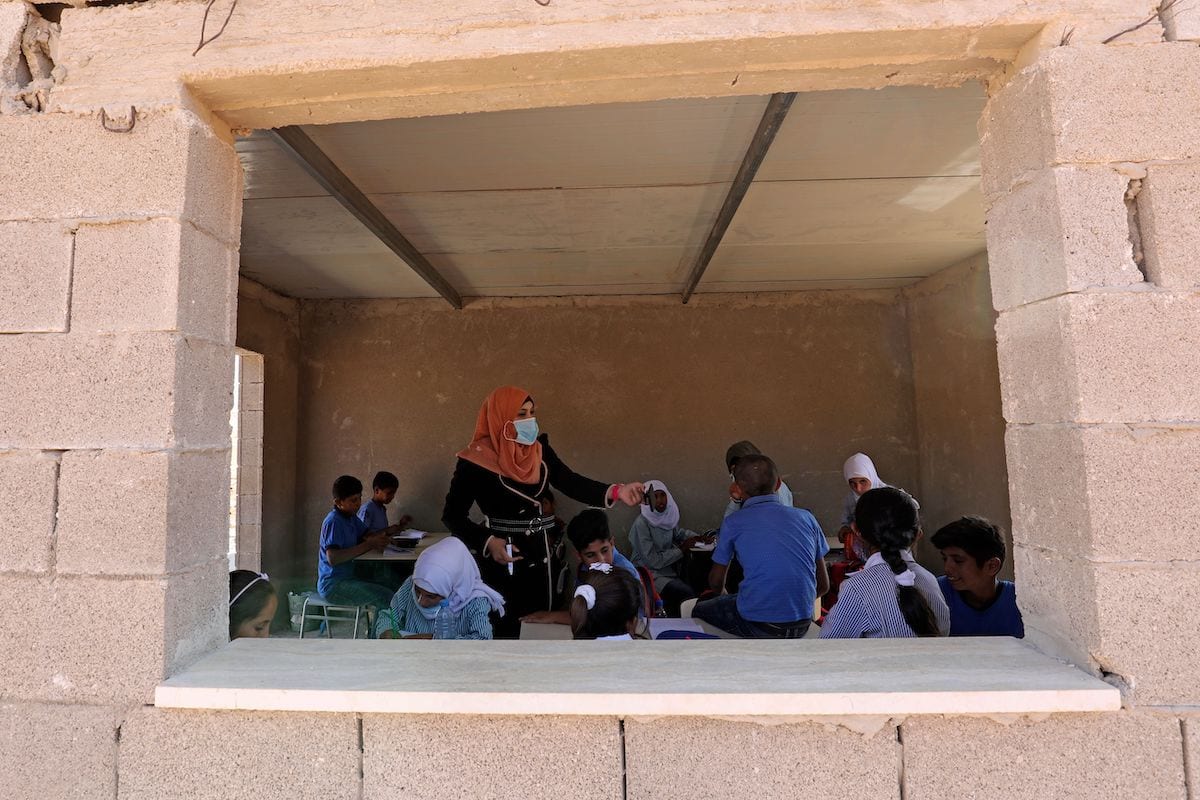 Palestinian students sit with their teacher inside a classroom at the Ras al-Tenneen school in eastern Ramallah city which an Israeli court ruled that it was built without the necessary construction permit and rejected an appeal against its imminent demolition, on 8 October 2020. [ABBAS MOMANI/AFP via Getty Images]