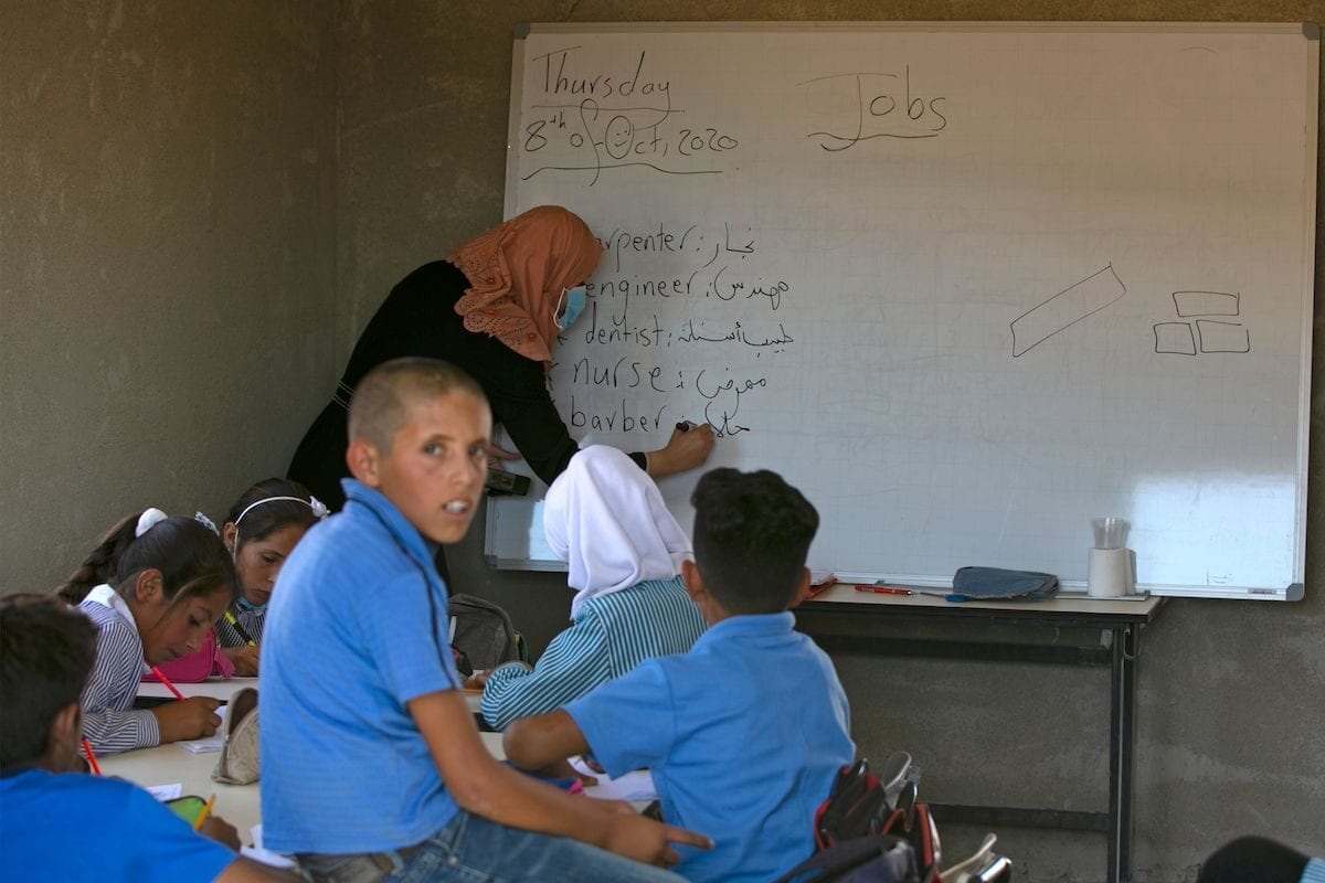 Palestinian students sit with their teacher inside a classroom at the Ras al-Tenneen school in eastern Ramallah city which an Israeli court ruled that it was built without the necessary construction permit and rejected an appeal against its imminent demolition, on 8 October 2020. [ABBAS MOMANI/AFP via Getty Images]
