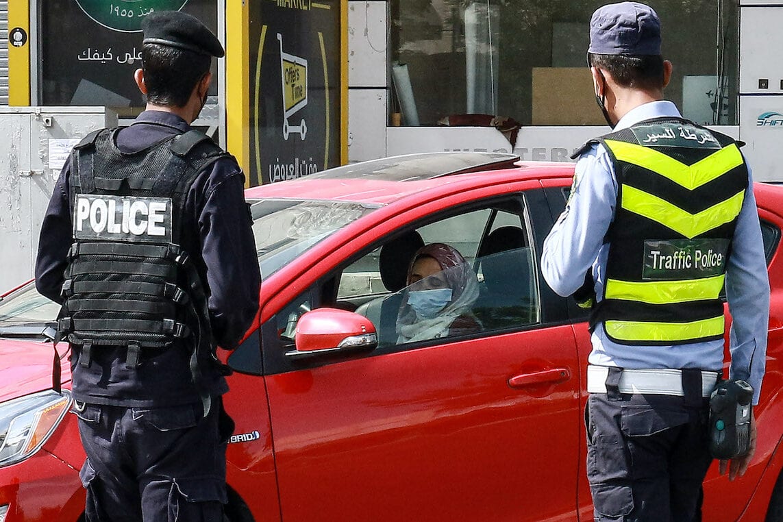 Jordanian policemen stop a vehicle and check the identification documents of its driver at a checkpoint during a COVID-19 coronavirus lockdown in the capital Amman on 9 October 2020. [KHALIL MAZRAAWI/afp/AFP via Getty Images]