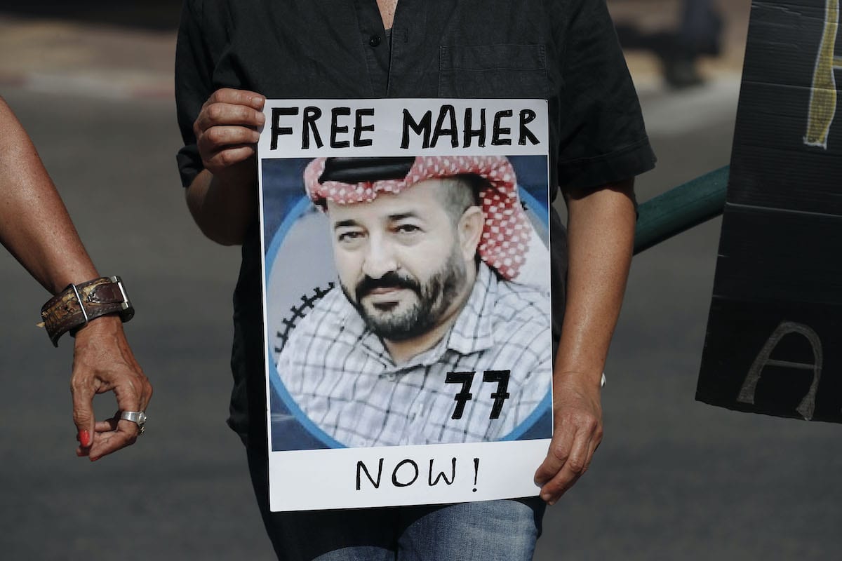 Israeli activists lift a placard bearing the picture of Palestinian administrative detainee Maher al-Akhras during a demonstration calling for his release on October 11, 2020 [AHMAD GHARABLI/AFP via Getty Images]