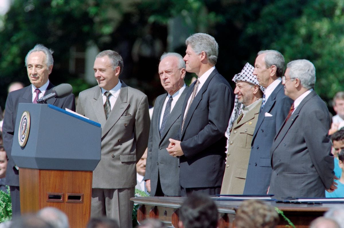 US President Bill Clinton (4th R) prepares to give the opening address of the historic Israel-PLO Oslo Accords signing ceremony on September 13, 1993 at the White House in Washington, D.C. next to Israeli Foreign Minister Shimon Peres (L), Russian Foreign Minister Andrei Kozyrev (2nd L), Israeli Prime Minister Yitzhak Rabin (3rd L), PLO Chairman Yasser Arafat (3rd R), US Secretary of State Warren Christopher (2nd R) and PLO political director Mahmoud Abbas (R). [LUKE FRAZZA/AFP via Getty Images]