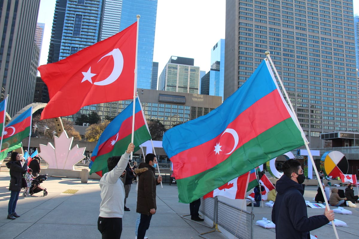 TORONTO, CANADA - NOVEMBER 14: A group of Azerbaijani people wave Azerbaijani and Turkish flags as they stage a protest by laying 93 pillows and red carnations with the names of 93 Azerbaijani civilians who killed during Armenian attacks, in front of the Toronto City Hall, Toronto, Canada on November 14, 2020. ( Seyit Aydoğan - Anadolu Agency )