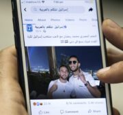 A man holds a phone showing a picture of Egypt's self-proclaimed "superstar" Mohamed Ramadan posted by the official Facebook page of the State of Israel in Arabic (linked to the foreign ministry) depicting Ramadan (R) hugging Israeli midfielder Dia Saba in Dubai on 22 November 2020 [KHALED DESOUKI/AFP via Getty Images]