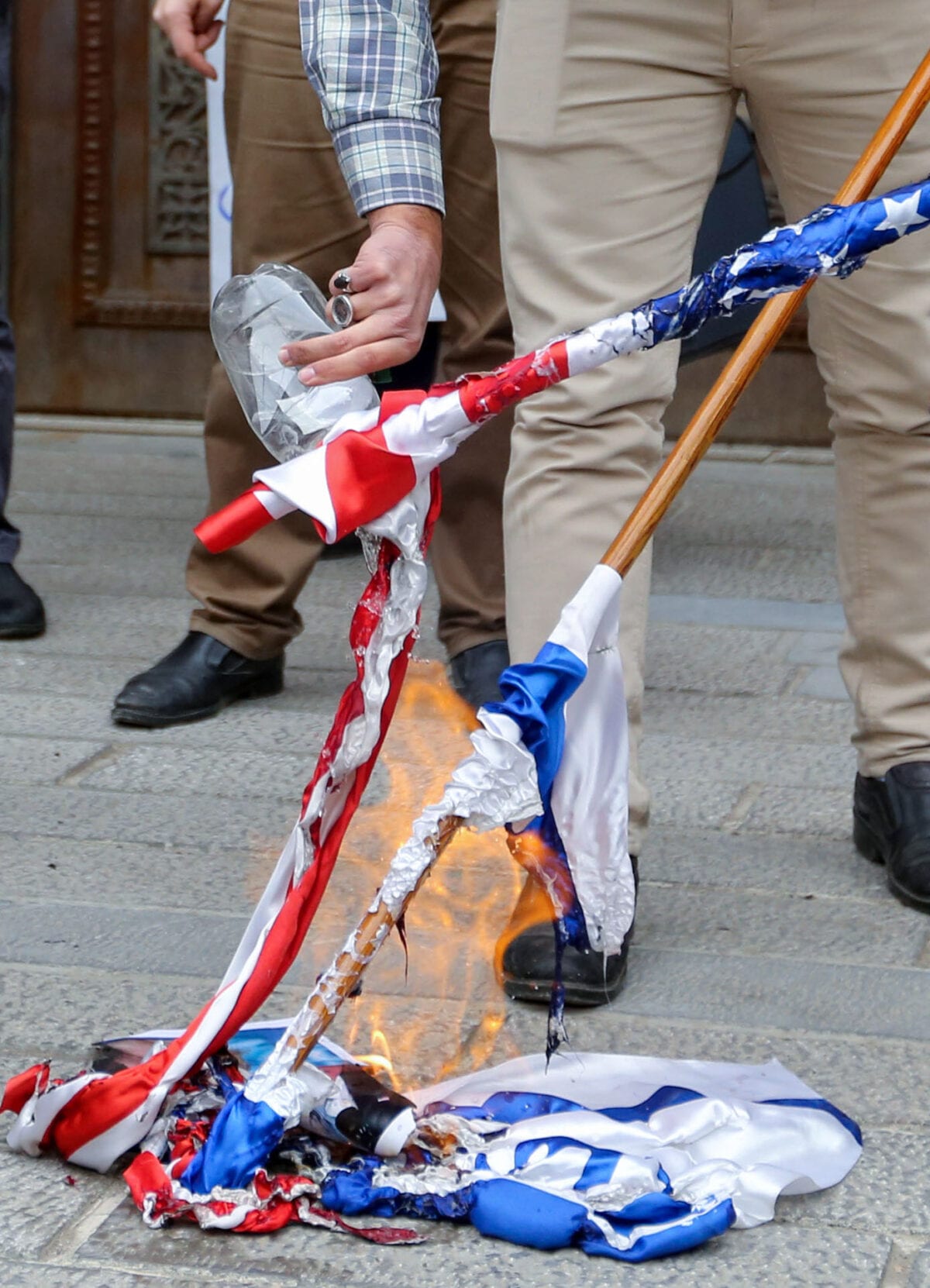 Students of Iran's Basij paramilitary force burn US and Israeli flags during a rally in front of the foreign ministry in Tehran, on November 28, 2020, to protest the killing of prominent nuclear scientist Mohsen Fakhrizadeh a day earlier near the capital. - Iran's President Hassan Rouhani accused arch-foe Israel of acting as a "mercenary" for the US and seeking to create chaos, blaming it for the assassination of a top Iranian nuclear scientist. (Photo by ATTA KENARE / AFP) (Photo by ATTA KENARE/AFP via Getty Images)