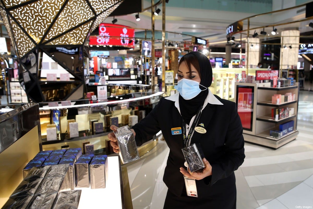 A duty-free employee, wearing a protective face mask due to the Covid-19 pandemic, restocks a shelf at the Muscat international airport in the Omani capital on October 1, 2020 [MOHAMMED MAHJOUB/AFP via Getty Images]