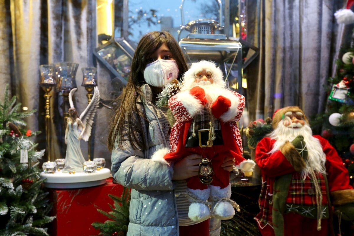 An Iranian girl, wearing a protective face mask, carries a stuffed Santa toy outside a shop selling Christmas decorations in the capital Tehran on December 22, 2020 [ATTA KENARE/AFP via Getty Images]