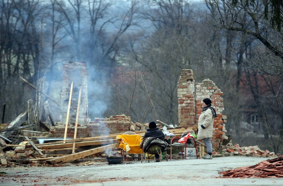 Two women gather in front of a destroyed home in Petrinja, Croatia on January 2 , 2021 [DAMIR SENCAR/AFP via Getty Images]