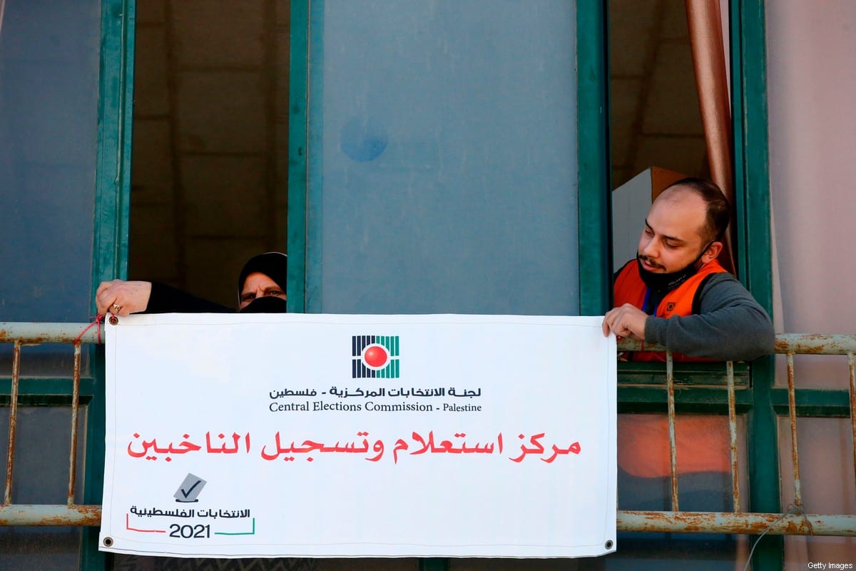 Members of the Palestinian Central Elections Commission hang a sign reading in Arabic "voter information and registration centre" in the West Bank town of Hebron on February 10, 2021 [HAZEM BADER/AFP via Getty Images]