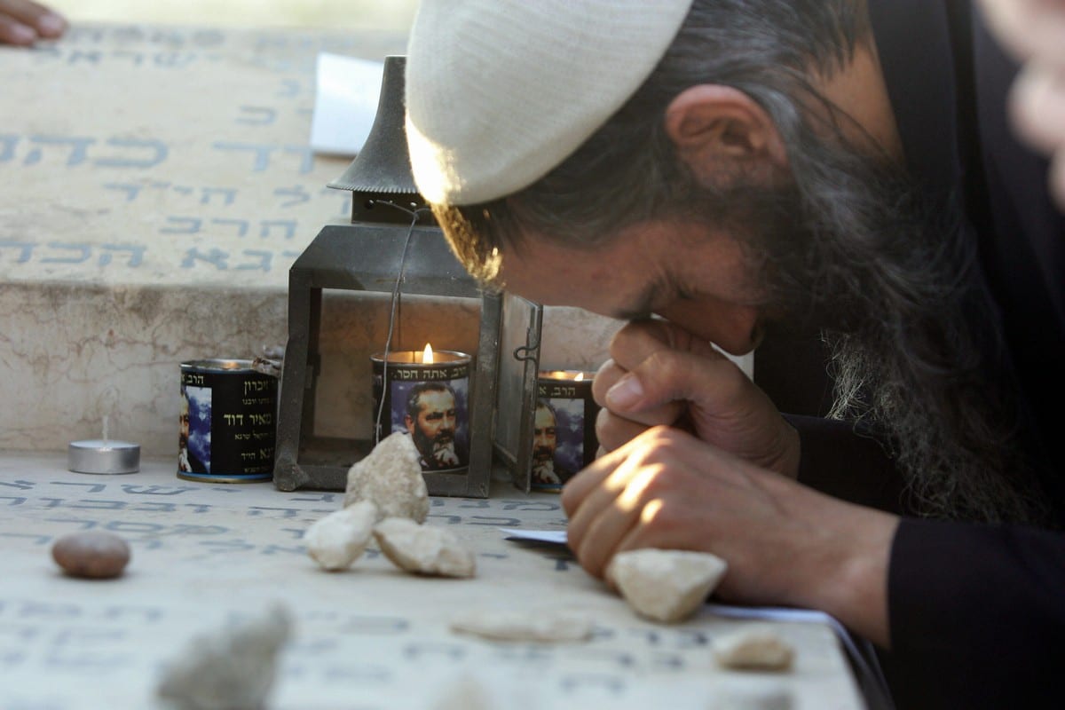 Candles burn with the image of the late Rabbi Meir Kahane at his grave in a cemetery on the outskirts of Jerusalem 9 November 2006 [MENAHEM KAHANA/AFP/Getty Images]
