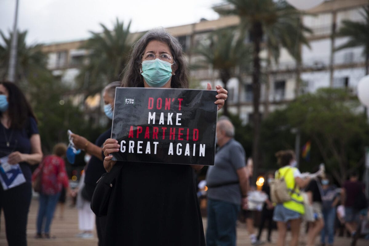 An Israeli woman holds a sign that reads "Don´t make Apartheid Great Again" as she protest against Israel goverment's plan on June 23, 2020 in Tel Aviv, Israel [Amir Levy/Getty Images]
