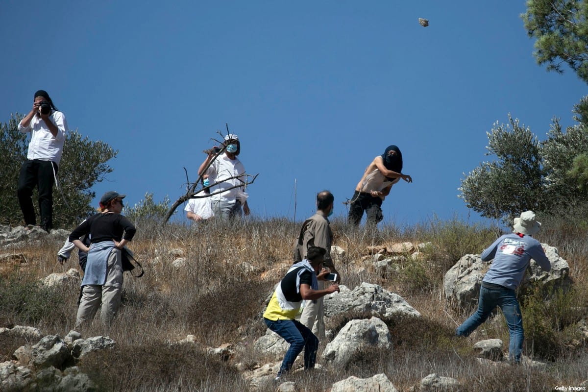 Masked Israeli settlers attack Palestinian olive farmers from the village of Hawara on fields near the settlement of Yitzhar in the Israeli-occupied West Bank, on October 7, 2020 [JAAFAR ASHTIYEH/AFP via Getty Images]