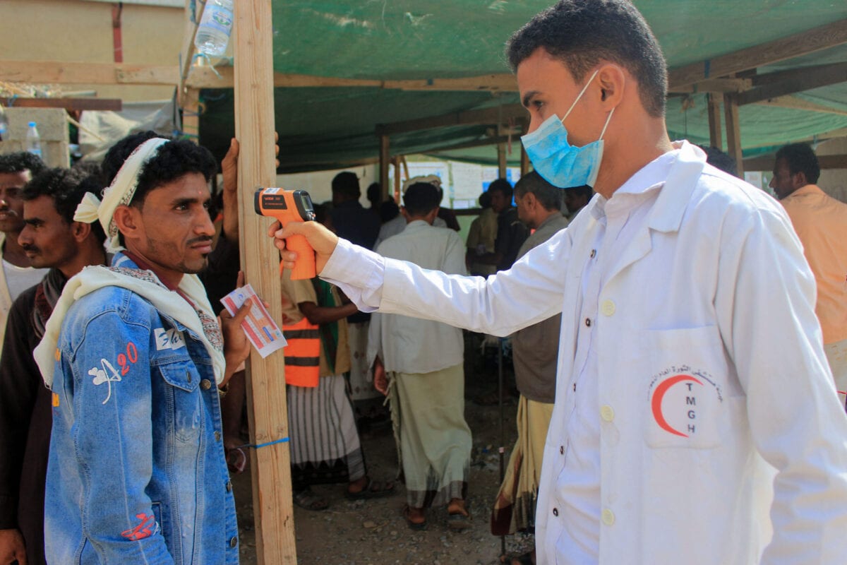 A healthcare worker checks the temperature of displaced Yemenis amid the COVID-19 pandemic on January 12, 2021 [ESSA AHMED/AFP via Getty Images]