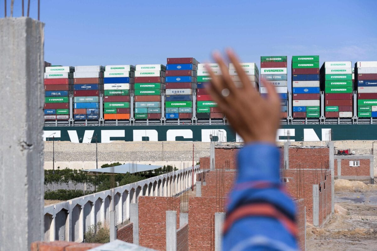 A man waves at the Panama-flagged MV 'Ever Given' container ship as it is tugged in Egypt's Suez Canal after it was fully dislodged from the banks, near Suez city, on March 29, 2021 [AHMAD HASSAN/AFP via Getty Images]