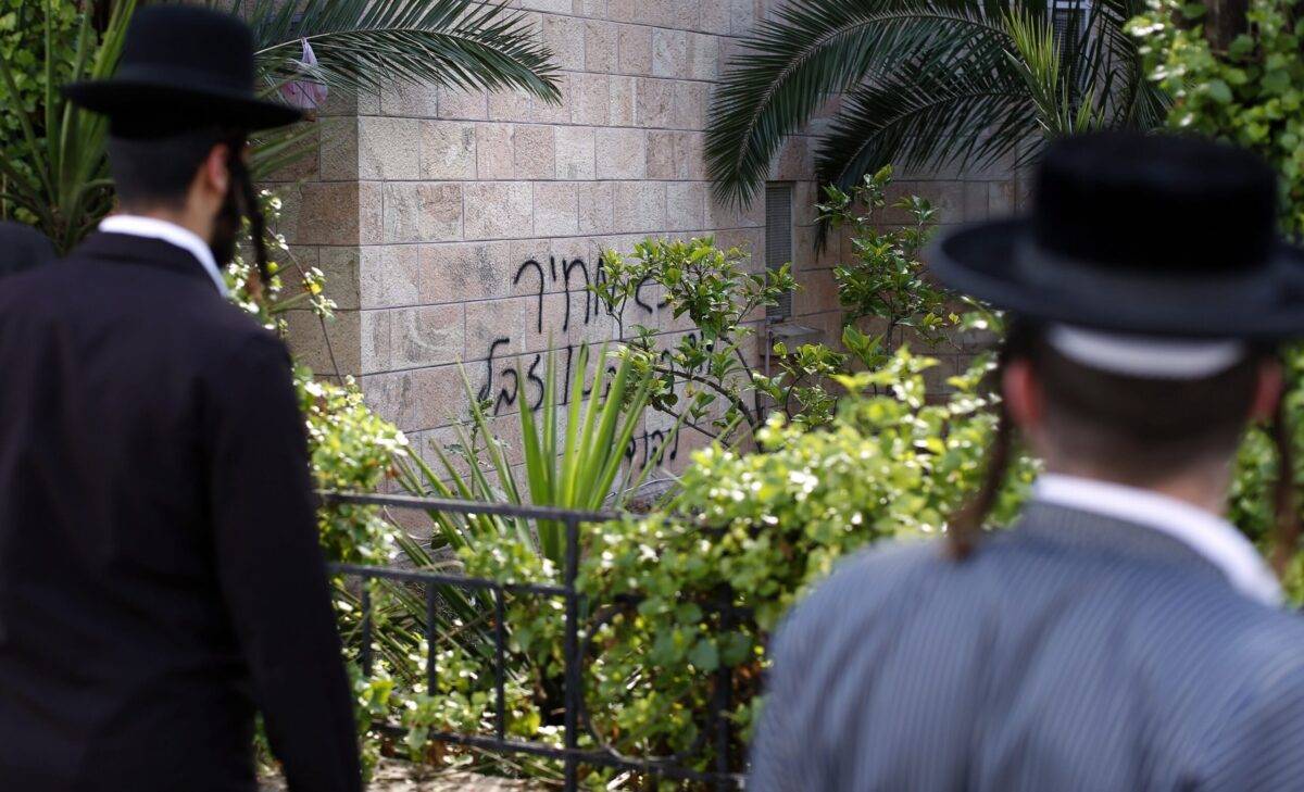 Two Ultra Orthodox Jews look at graffiti on the wall of a church reading in Hebrew "King David king of the Jews and Jesus is garbage, Price tag" on May 9, 2014 in Jerusalem [THOMAS COEX/AFP via Getty Images]