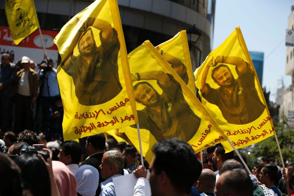 Protesters wave flags bearing a portrait of prominent jailed Palestinian Marwan Barghouti during a rally in the West Bank city of Ramallah on April 17, 2017 [ABBAS MOMANI/AFP via Getty Images]