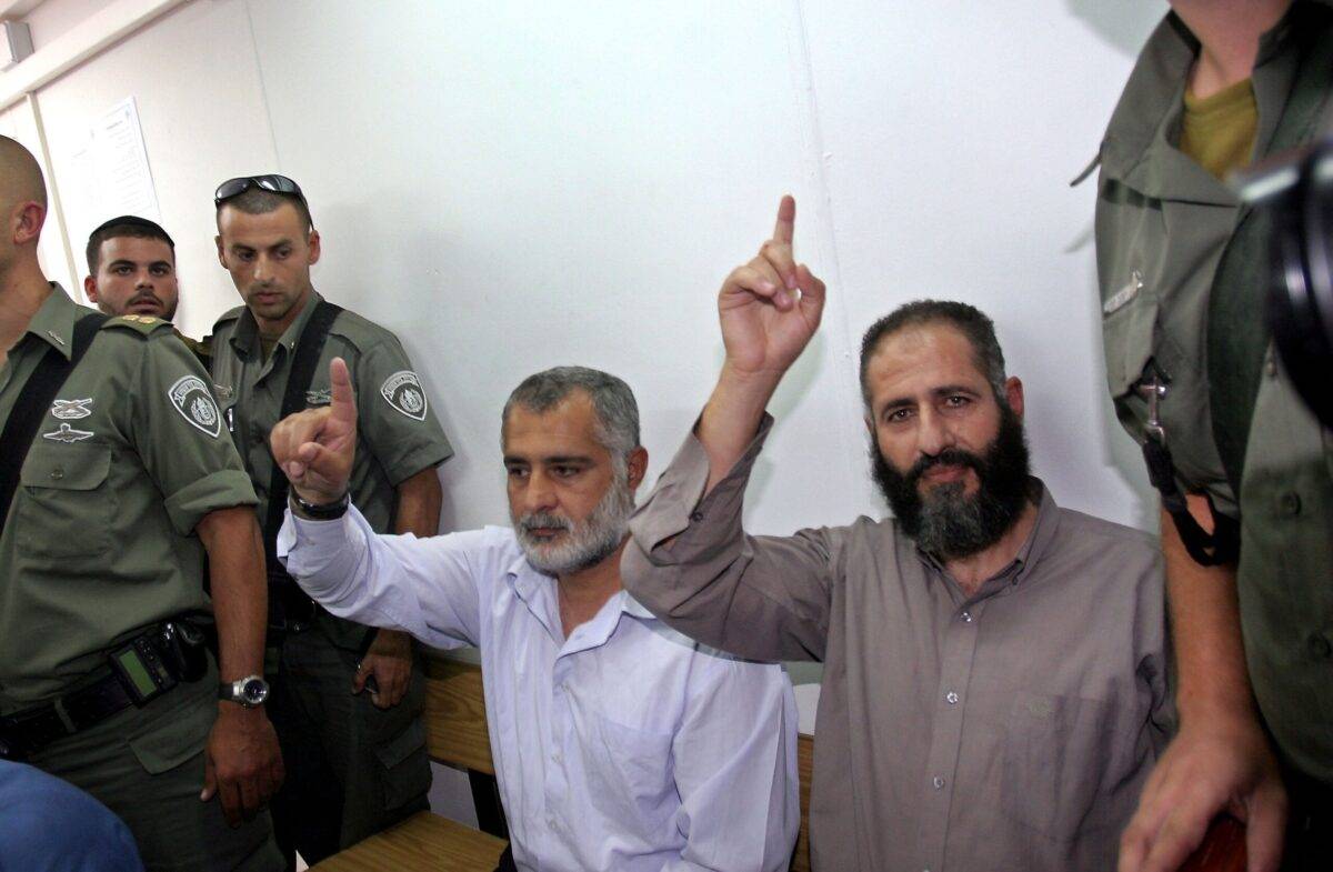 Hamas activist Nayef Rajoub (R) and another unidentified activist, make Islamic salutes as five members of the militant Islamic group are brought by Israeli border-police into an Israeli military court for a remand hearing July 5, 2006 at Ofer army base in the West Bank [Brian Hendler/Getty Images]