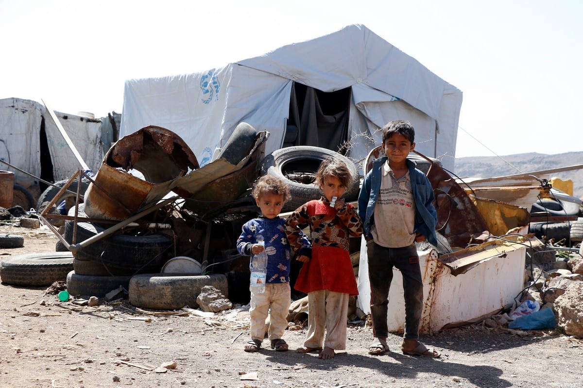 Children who were displaced due to the ongoing war stand beside tents at an internally displaced camp on February 21, 2021 [Mohammed Hamoud/Getty Images]