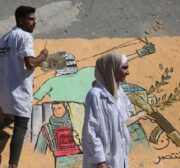 Palestinian artists draw murals on the ruins of Al-Shurouk Tower in Gaza to highlight the people’s steadfastness on 25 May 2021 [Mohammed Asad/Middle East Monitor]