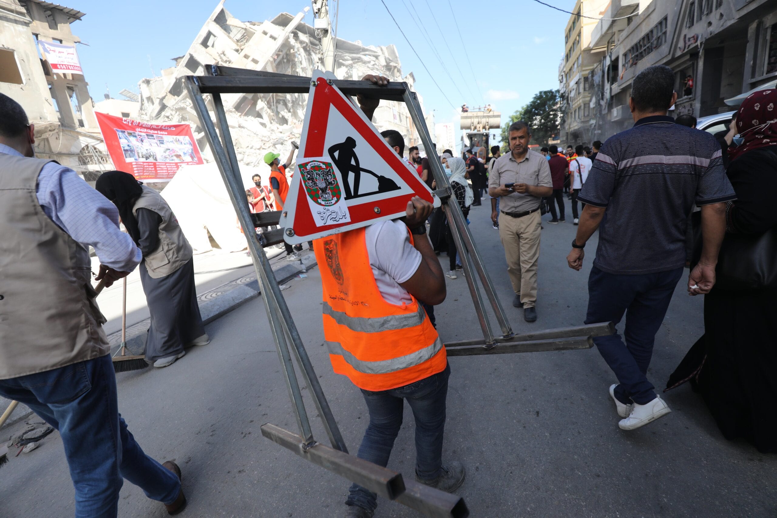 Palestinian volunteers sweep the rubble of buildings destroyed by
