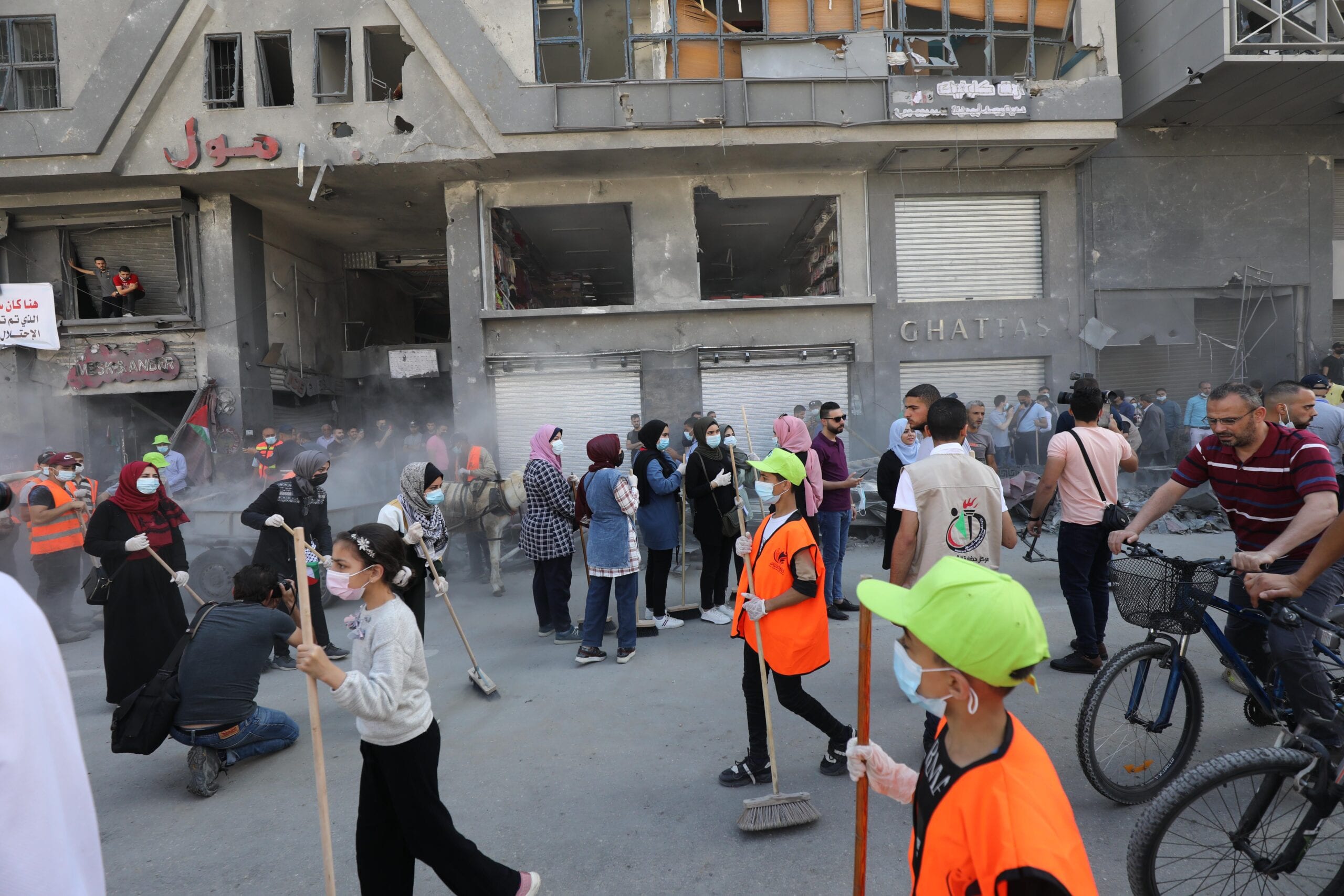 Palestinian volunteers sweep the rubble of buildings destroyed by