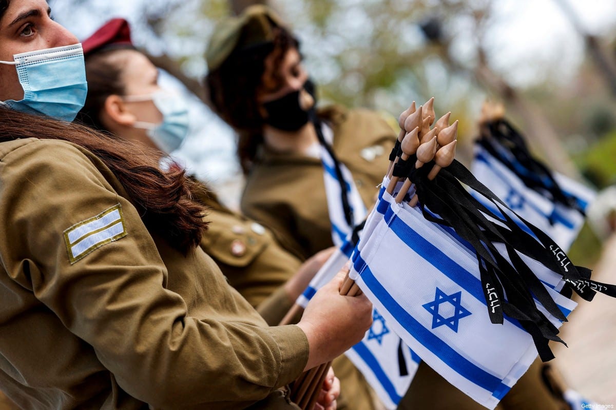 Female soldiers hold Israeli national flags in Tel Aviv on 13 April 2021 [JACK GUEZ/AFP via Getty Images]