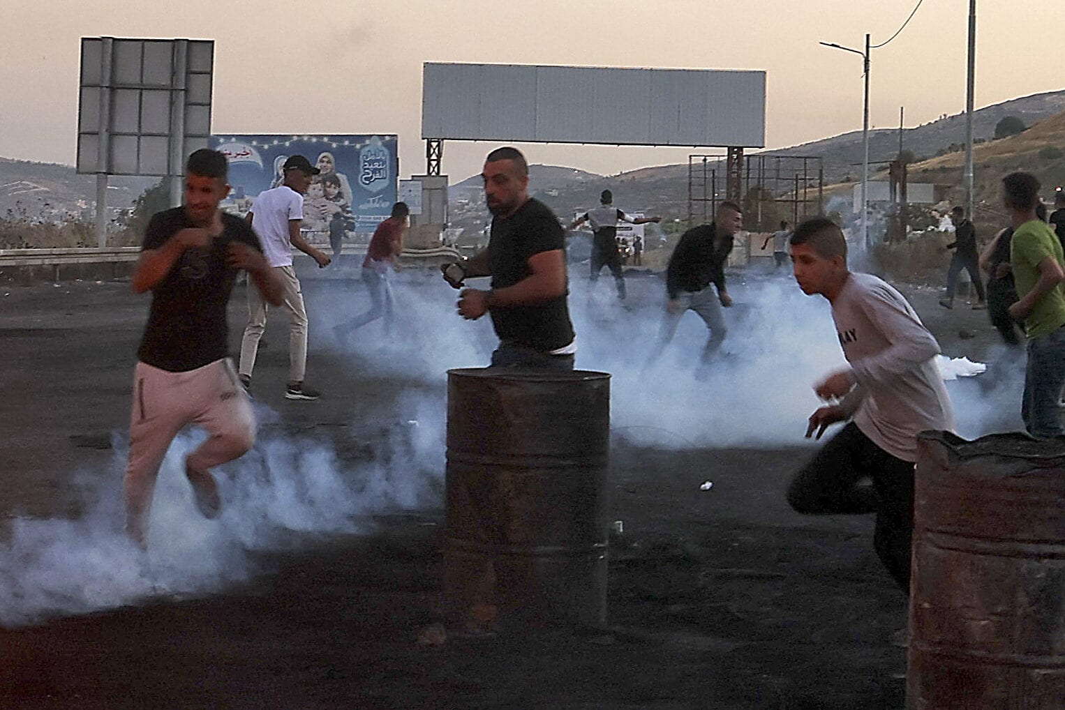 Palestinian protesters rush off to avoid tear gas amid clashes with Israeli security forces at the Hawara checkpoint south of Nablus city, in the occupied West Bank, on May 16, 2021 [AAFAR ASHTIYEH/AFP via Getty Images]