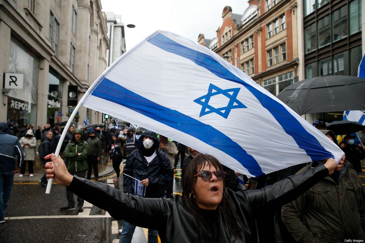 A protestor holds an Israeli flag during a Pro-Israel demonstration outside the Israeli Embassy on May 23, 2021 in London, England [Hollie Adams/Getty Images]
