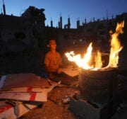 A Palestinian boy sits near a fire amid buildings damaged by the Israeli attacks in Beit Lahia, Gaza on June 07, 2021. Palestinians continue their daily lives amid rubbles, damaged and destroyed buildings and cars [Ashraf Amra - Anadolu Agency]