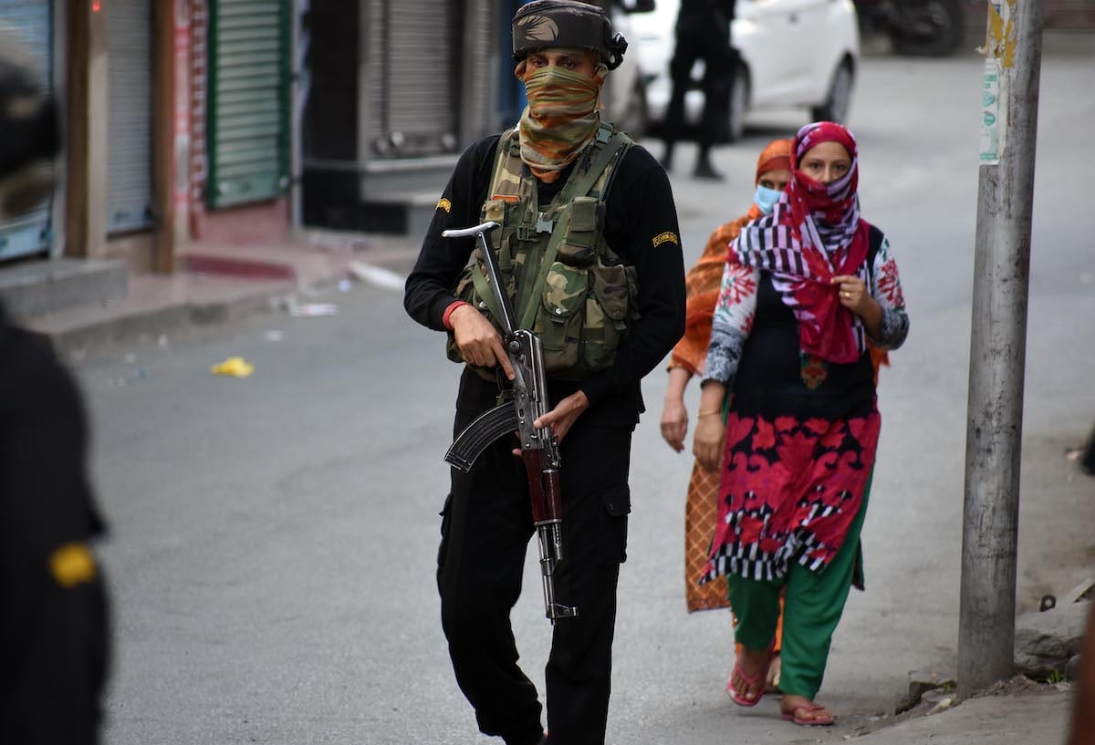 SRINAGAR, KASHMIR, INDIA-JUNE 26 : Kashmiri women walk past an Indian policeman of Special Operation Group (SOG) near the site of attack in Barbar Shah area of Srinagar,Kashmir on June 26, 2021. Four civilians including a non-local were injured after suspected militants lobbed a grenade at Indian forces in Barbar Shah Srinagar ,Police said. ( Faisal Khan - Anadolu Agency )