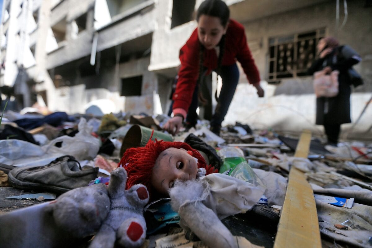 A girl looks through abandoned belongings in the rubble on the streets of the Palestinian Yarmuk camp, on the southern outskirts of the Syrian capital Damascus, on November 25, 2020 [LOUAI BESHARA/AFP via Getty Images]