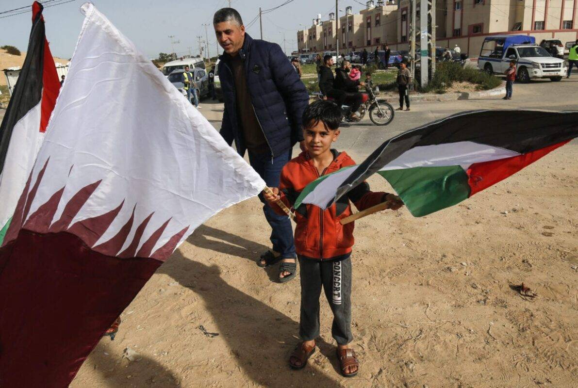 A Palestinian boy waves the Qatari and Palestinian flags on February 8, 2021 [SAID KHATIB/AFP via Getty Images]