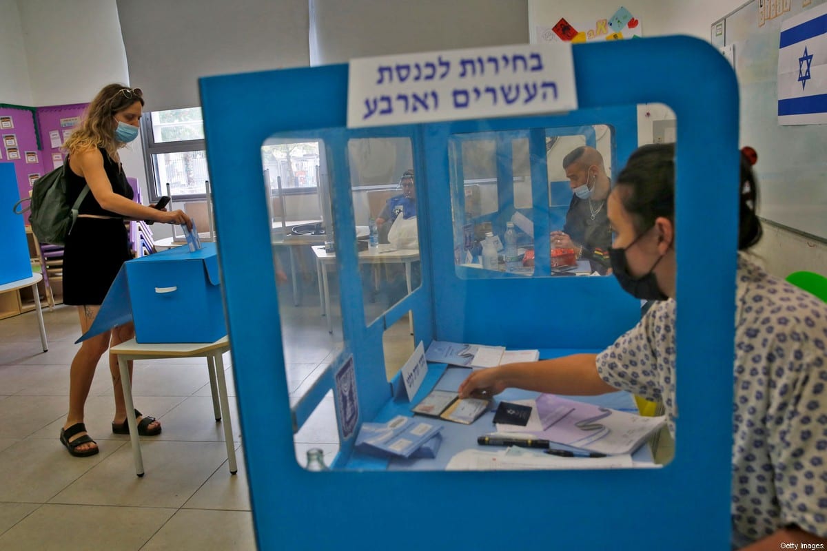 An Israeli voter casts her ballot at a polling station in the coastal city of Tel Aviv on March 23, 2021 [GIL COHEN-MAGEN/AFP via Getty Images]