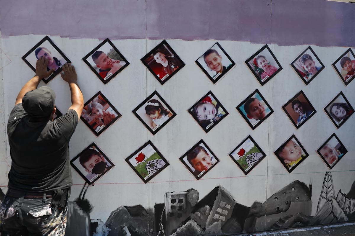 Pictures of Palestinian children killed in the Israeli attack on Gaza in May 2021 are placed outside the UNDP office on 13 July 2021 [Mohammed Asad/Middle East Monitor]