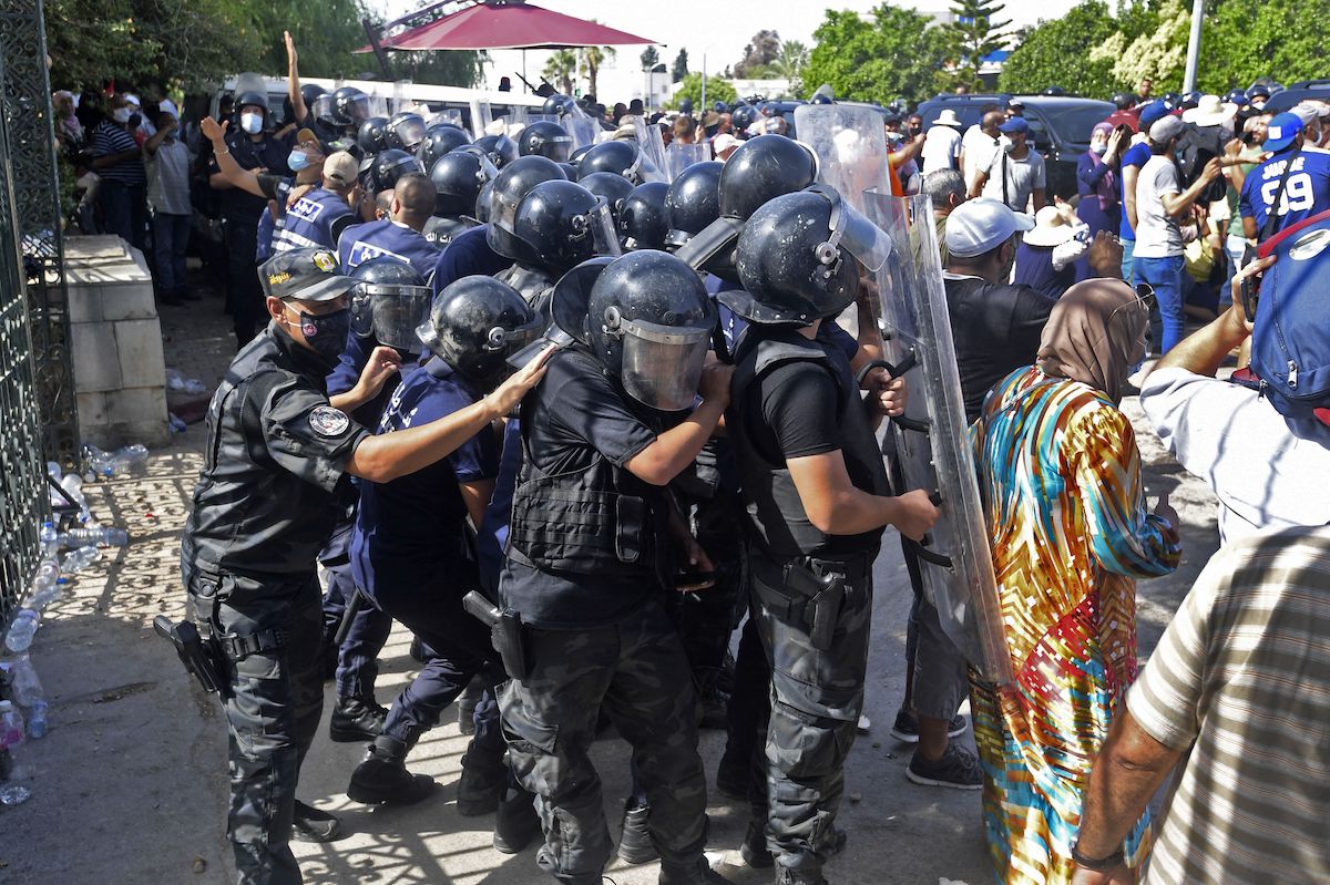 Tunisian security officers hold back protesters outside the parliament building in the capital Tunis on 26 July 2021, following a move by the president to suspend the country's parliament and dismiss the Prime Minister. [FETHI BELAID/AFP via Getty Images]