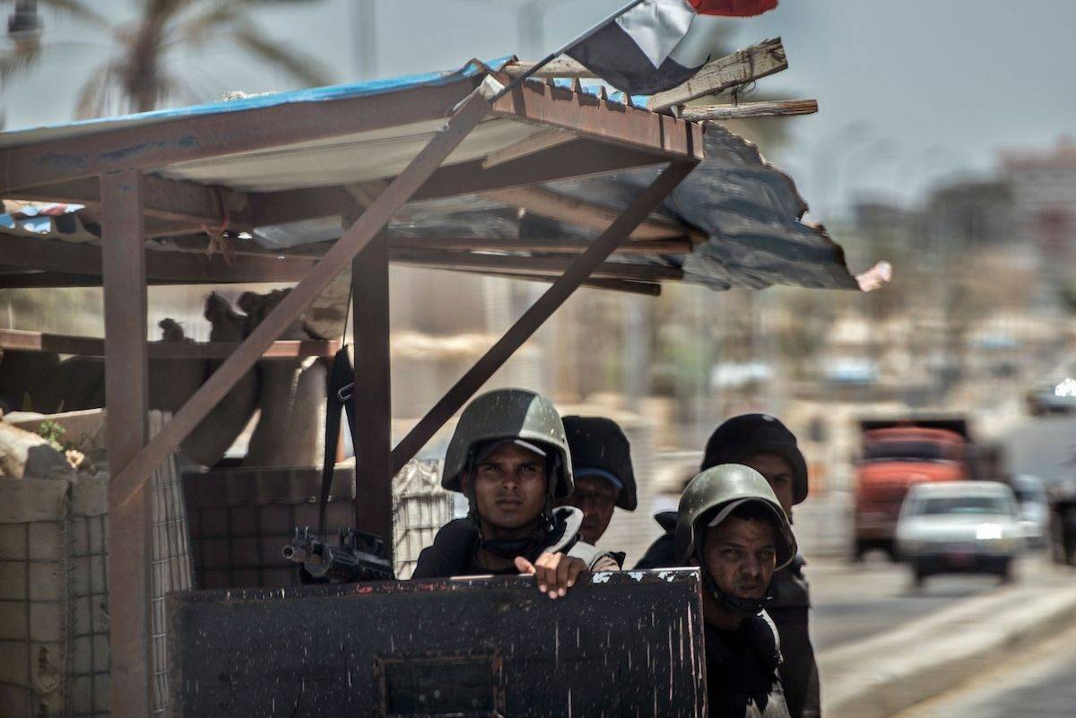 A picture taken on July 26, 2018 shows Egyptian policemen stand guarding a checkpoint on a road leading to the North Sinai provincial capital of El-Arish. [KHALED DESOUKI/AFP via Getty Images]