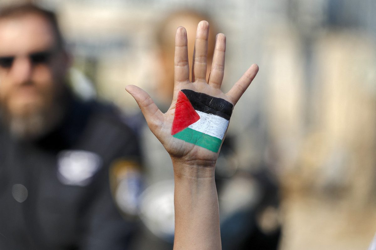 A demonstrator raises her hand, painted with the colours of the Palestinian flag, during a demonstration by Palestinian, Israeli, and foreign activists against Israeli occupation and settlement activity in the Palestinian Territories and east Jerusalem, in Jerusalem's Palestinian Sheikh Jarrah neighbourhood on 30 July 2021. [AHMAD GHARABLI/AFP via Getty Images]