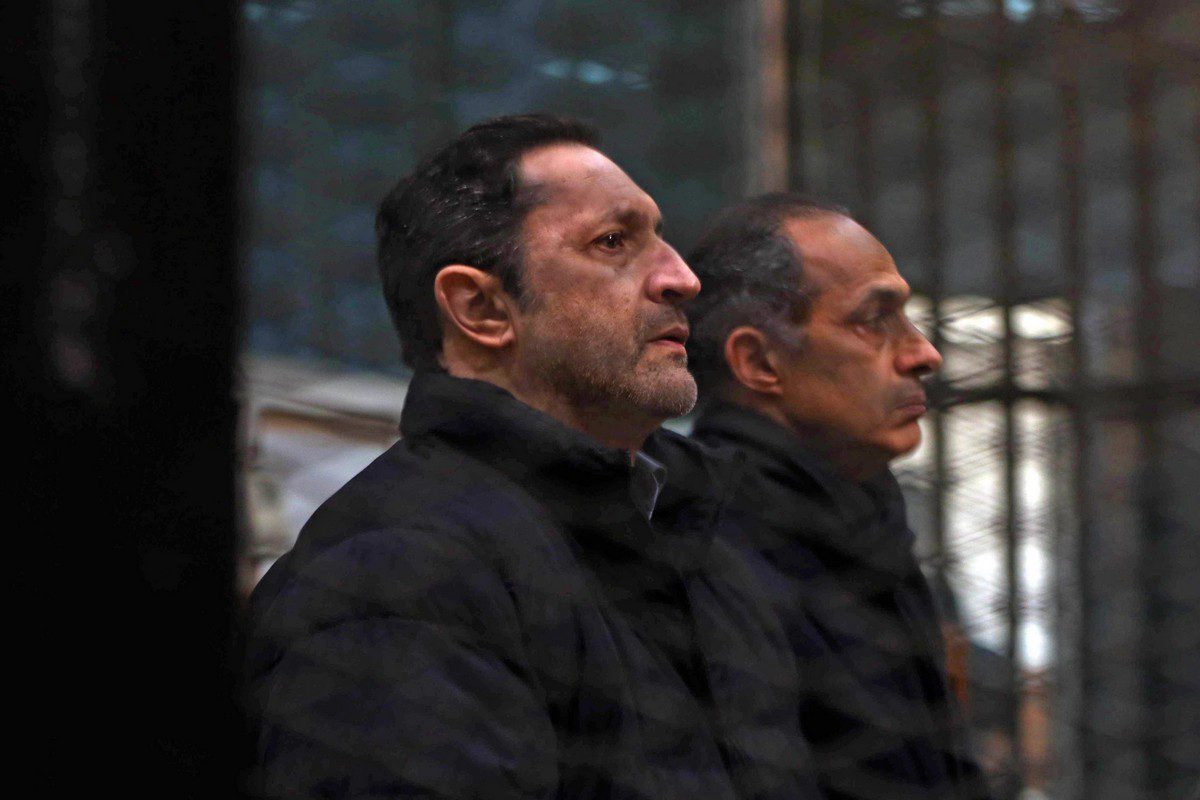 (L to R) Alaa and Gamal Mubarak, sons of former Egyptian president Hosni Mubarak, sit inside the defendants' cage at the Police Academy courthouse in Cairo on 22 February 2020 [AFP/Getty Images]