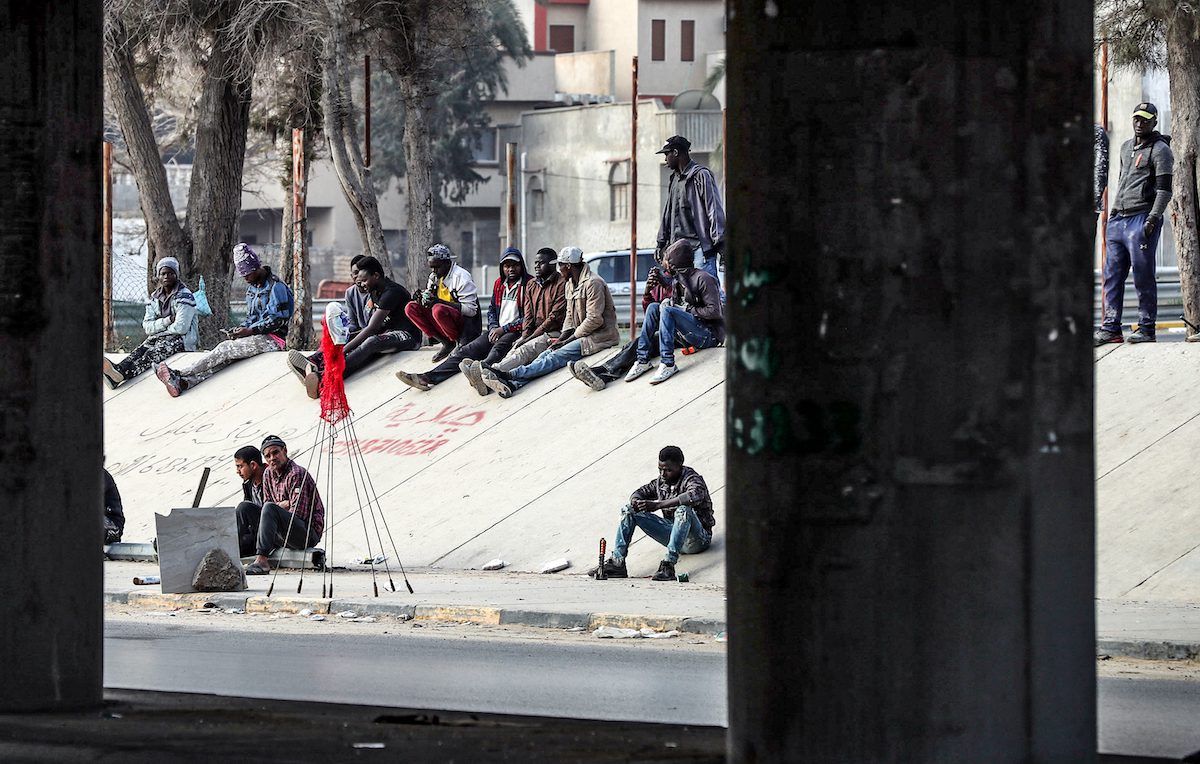 African migrant day labourers seeking small jobs, wait under a bridge in the Libyan capital Tripoli to be hired by potential employers, on 6 March 2021. [MAHMUD TURKIA/AFP via Getty Images]