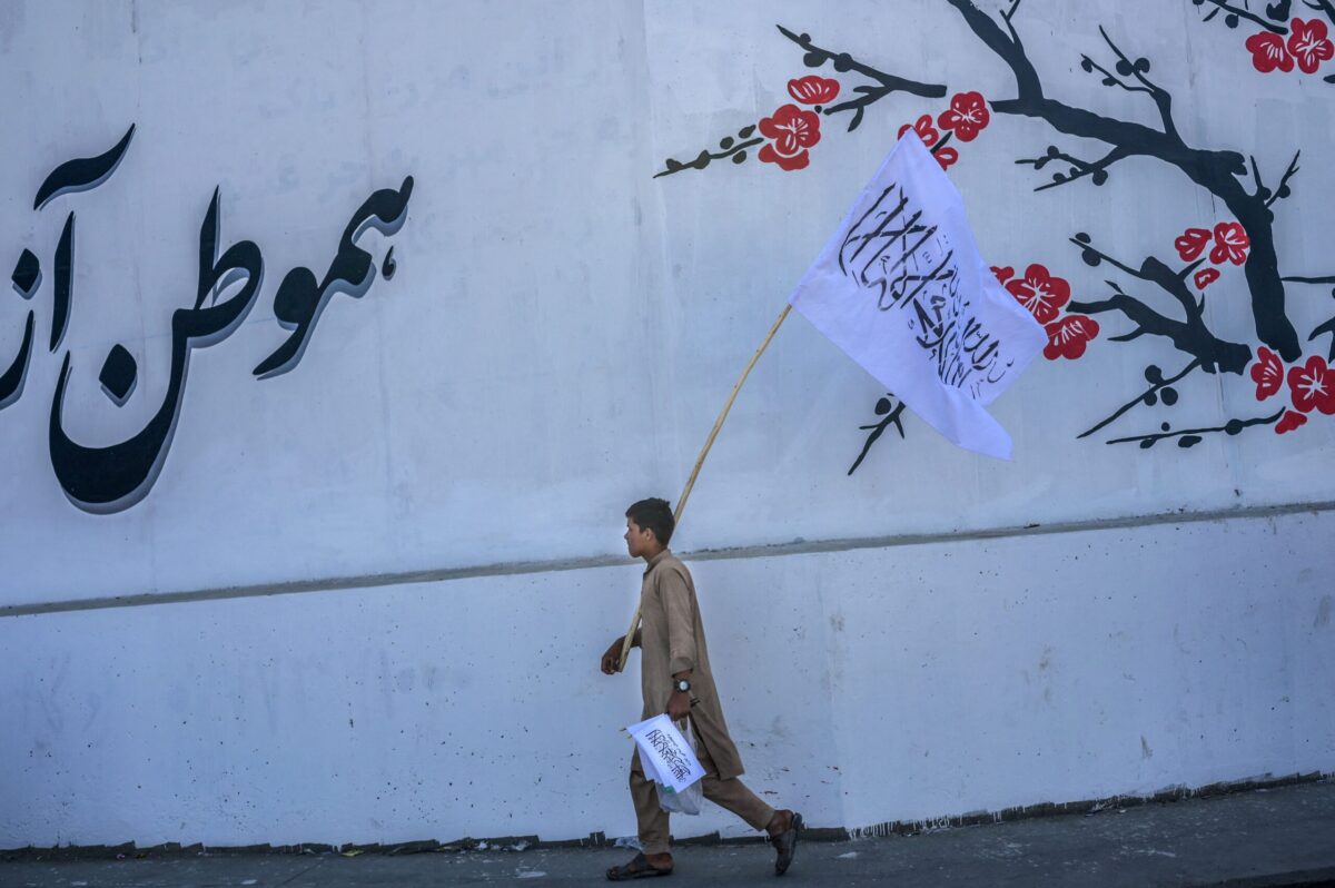 A boy walks along a street selling Taliban flags in Kabul on September 16, 2021 [BULENT KILIC/AFP via Getty Images]