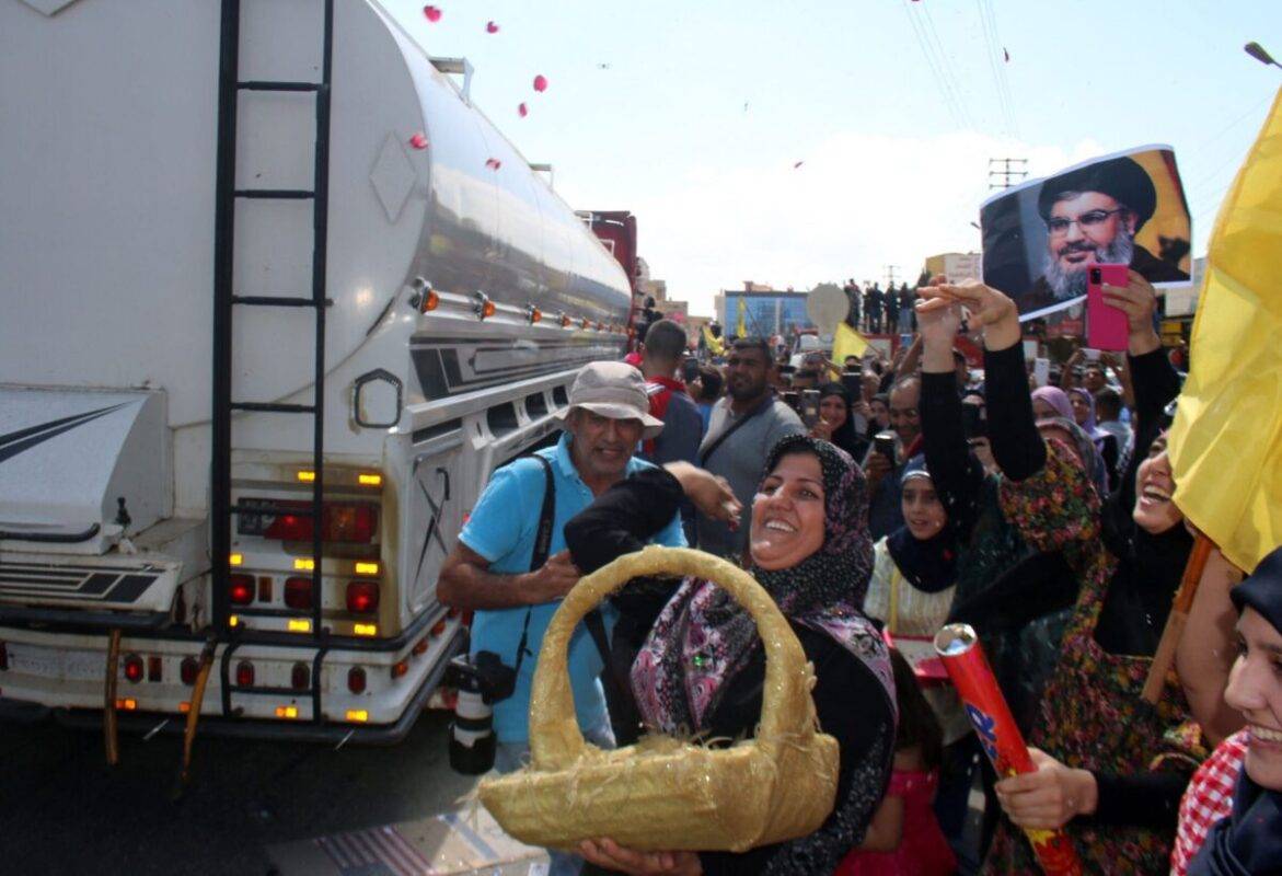 A woman tosses rose petals as people gather to welcome tankers carrying Iranian fuel, upon their arrival from Syria in the city of Baalbeck, in Lebanon's Bekaa valley, on September 16, 2021 [AFP via Getty Images]
