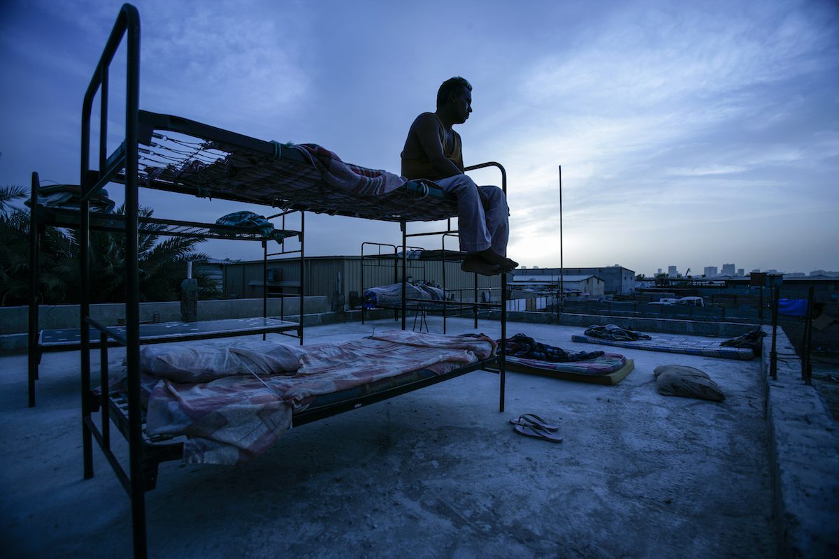 An abandoned migrant labourer sits on a rooftop in a squallid makeshift camp in Sharjah, the Emirate next to Dubai. [Brent Stirton/Getty Images]