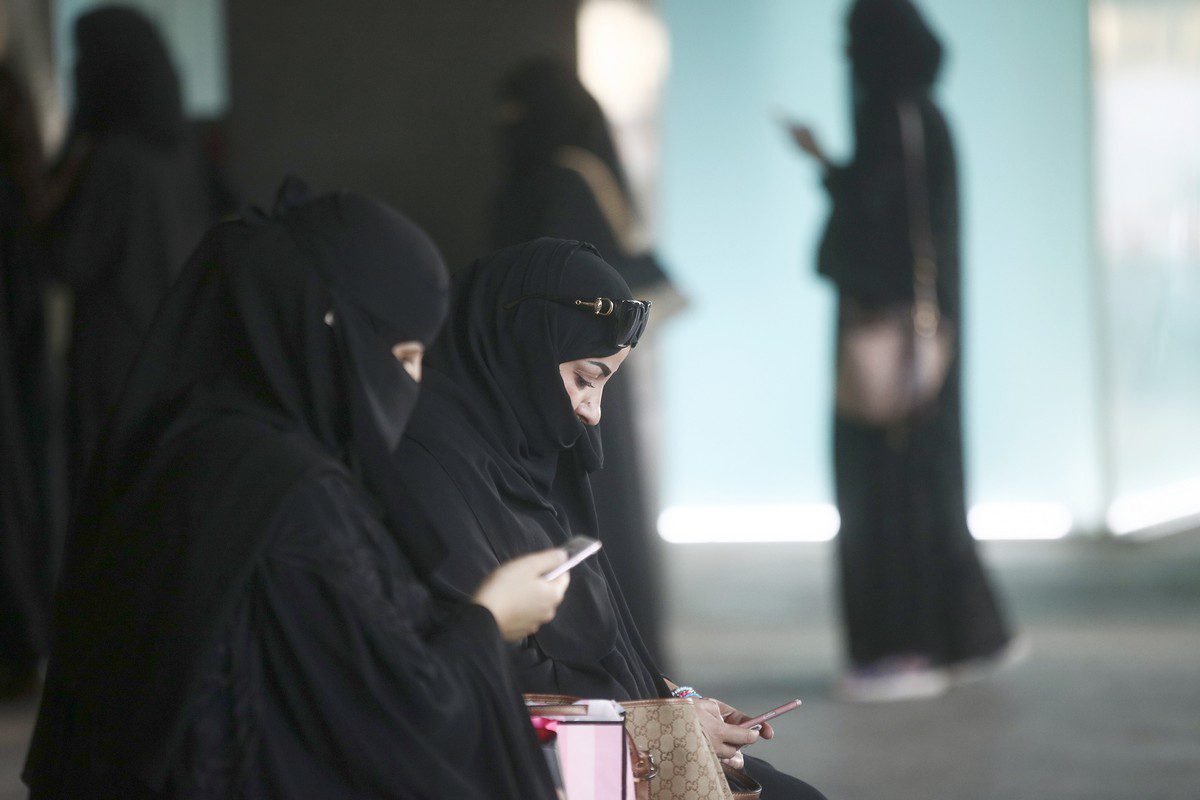 Shoppers check their smartphones whilst waiting for transport in Riyadh, Saudi Arabia, on 2 December 2016 [Simon Dawson/Bloomberg/Getty Images]