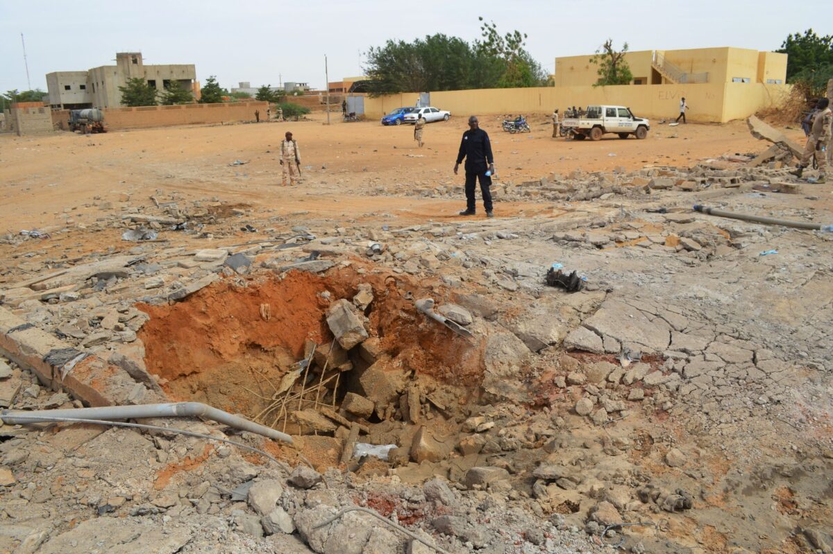 Malian soldiers stand near a hole in the ground caused by the explosion of a suicide car bomb attack overnight, which killed three people, on November 13, 2018, in Gao [STR/AFP via Getty Images]