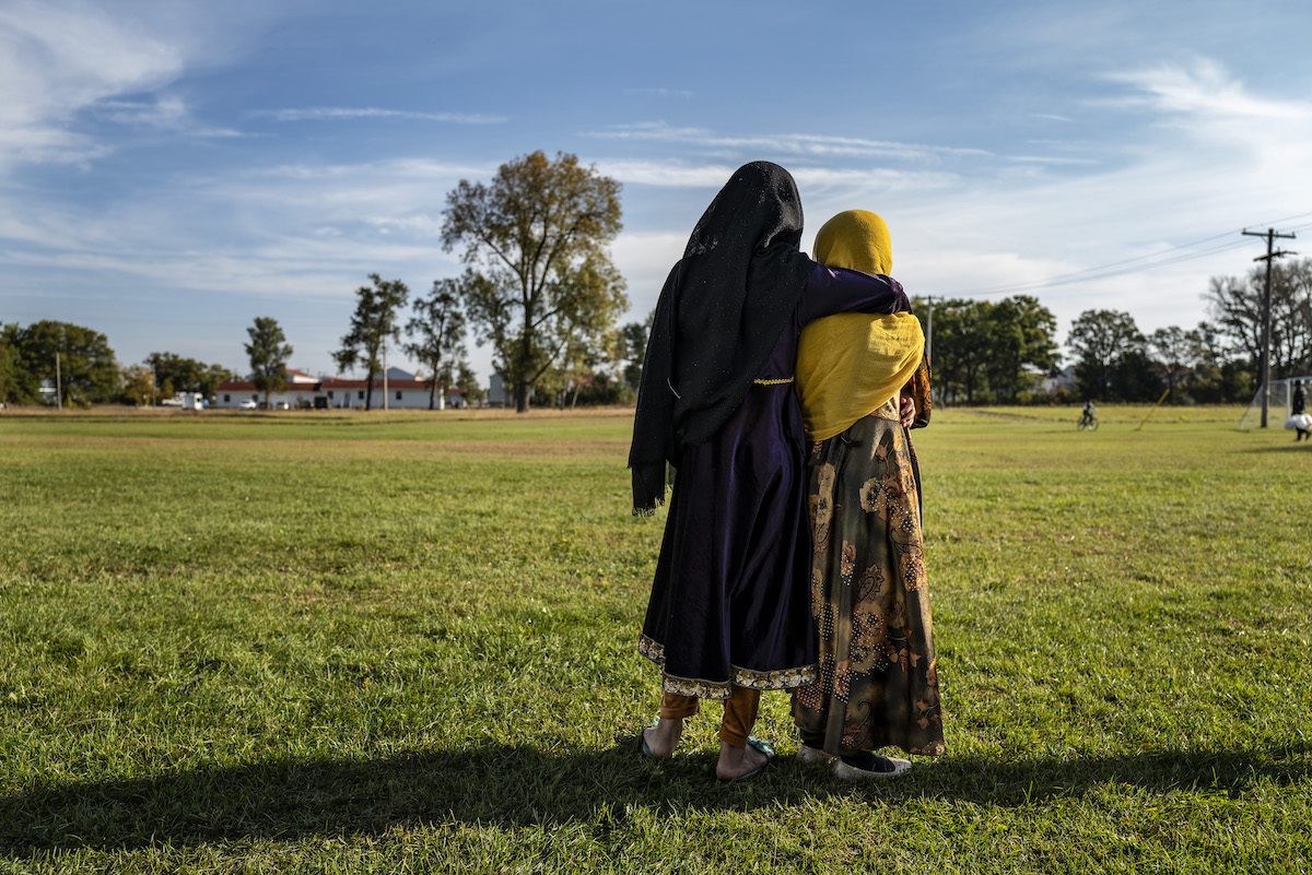 Afghan refugee girls watch a soccer match near where they are staying in the Village at the Ft. McCoy U.S. Army base on 30 September 2021 in Ft. McCoy, Wisconsin. [Barbara Davidson/Getty Images]
