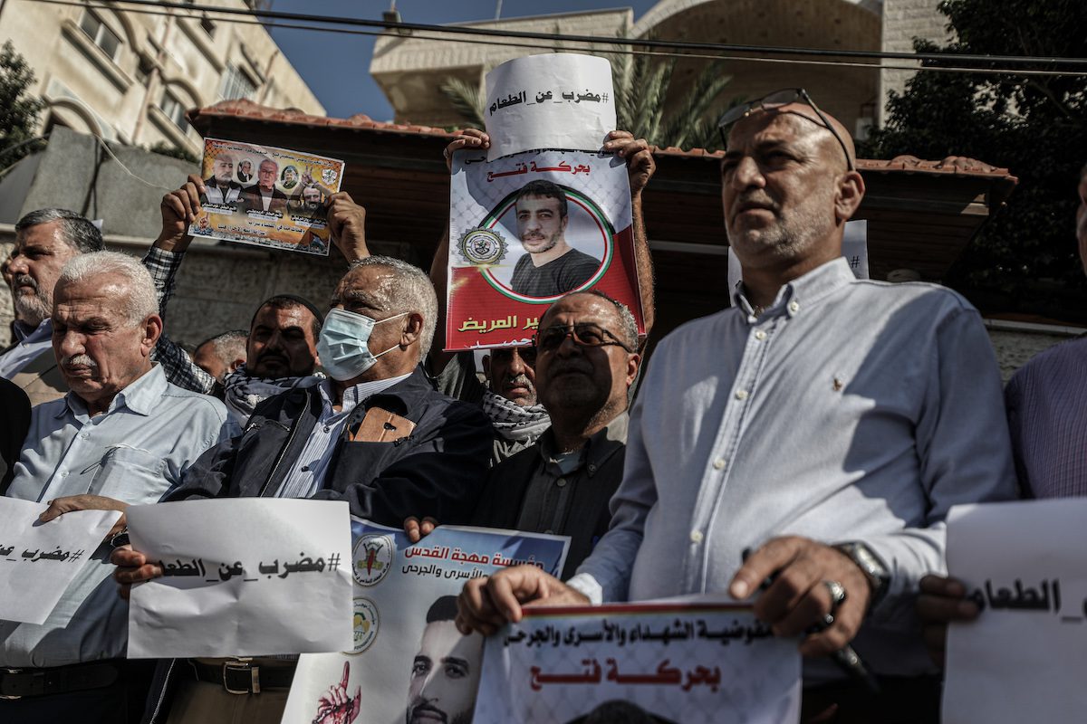 Palestinians hold banners during a demonstration in support of Palestinian prisoners on hunger strike in Israeli jails against Israel's administrative detention on 3 November 2021 [Ali Jadallah/Anadolu Agency]