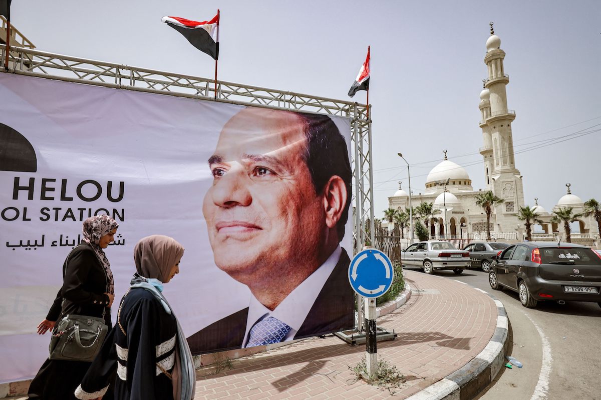 Women walk past a giant banner depicting Egypt's President Abdel Fattah al-Sisi amidst preparations to receive a visiting Egyptian intelligence delegation in Gaza City on 31 May 2021. [MOHAMMED ABED/AFP via Getty Images]