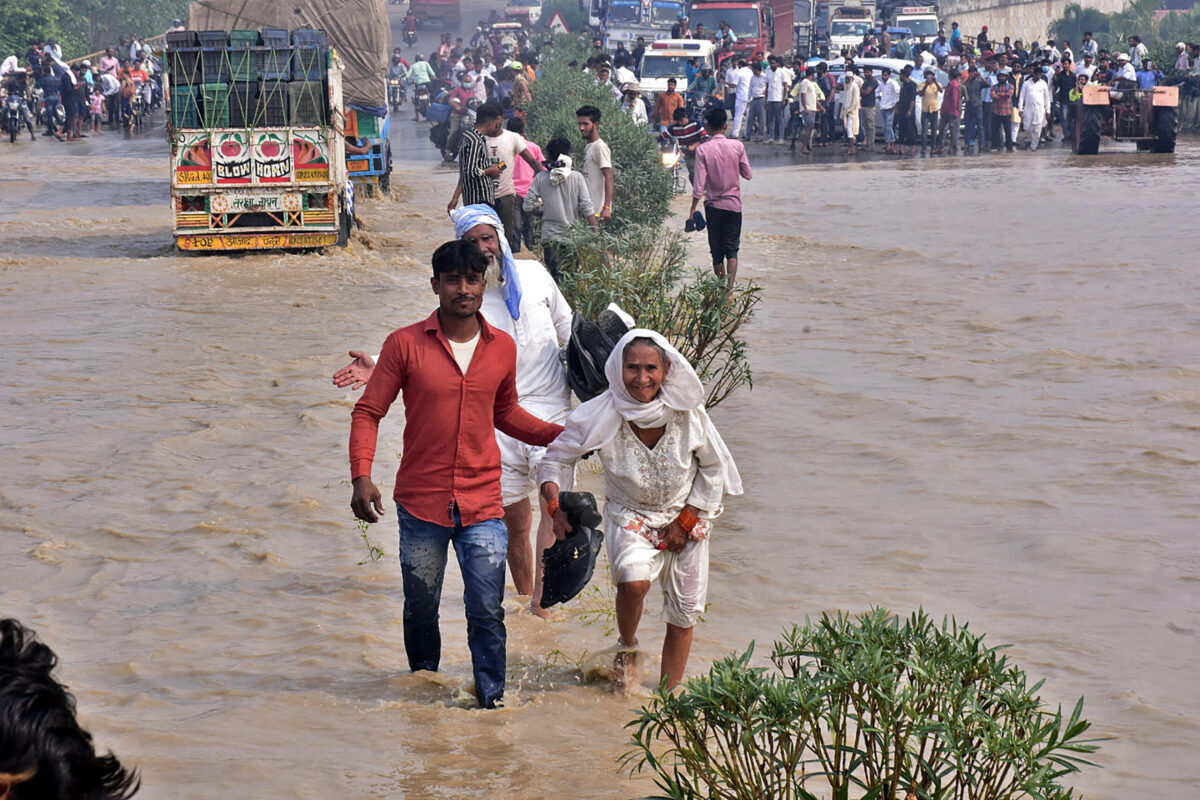 TOPSHOT - Commuters wade through a flooded national highway after river Kosi overflowed following heavy rains near Rampur in India's Uttar Pradesh state on October 20, 2021, as the death toll from days of flooding and landslides in India and Nepal crossed 100. (Photo by AFP) (Photo by -/AFP via Getty Images)