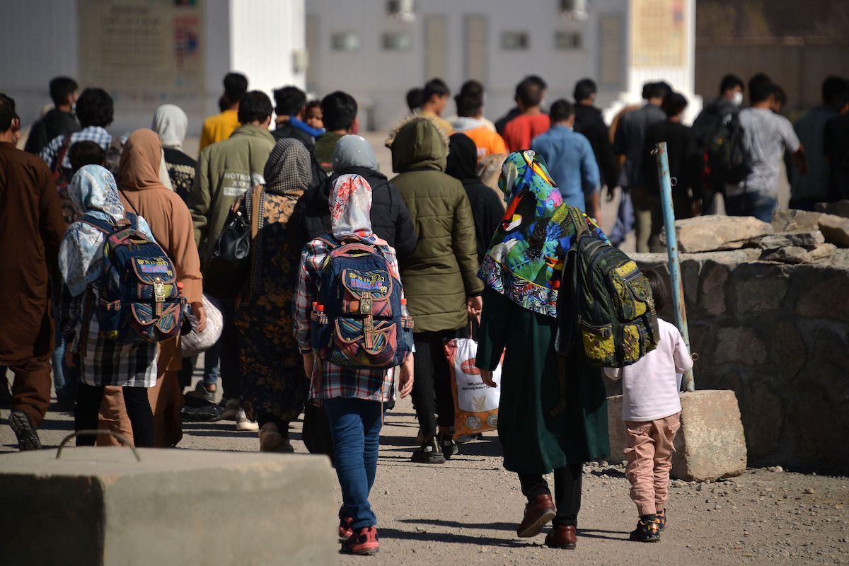 In this picture taken on October 19, 2021 Afghans who were forcibly deported back from Iran to Afghanistan walk towards the border between Afghanistan and Iran at Islam Qala port. [HOSHANG HASHIMI/AFP via Getty Images]